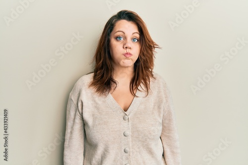 Young caucasian woman wearing casual clothes puffing cheeks with funny face. mouth inflated with air, crazy expression.