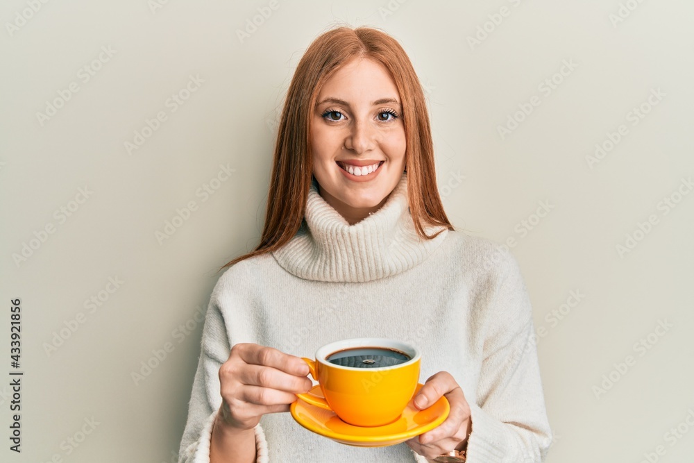 Young irish woman drinking a cup of coffee smiling with a happy and cool smile on face. showing teeth. Young irish woman drinking a cup of coffee smiling with a happy and cool smile on face. showing teeth.