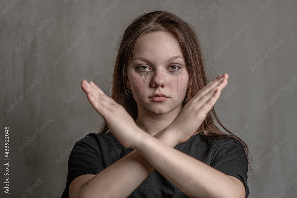 Unhappy teenage girl shows stop gesture with crossed hands Unhappy teenage girl shows stop gesture with crossed hands