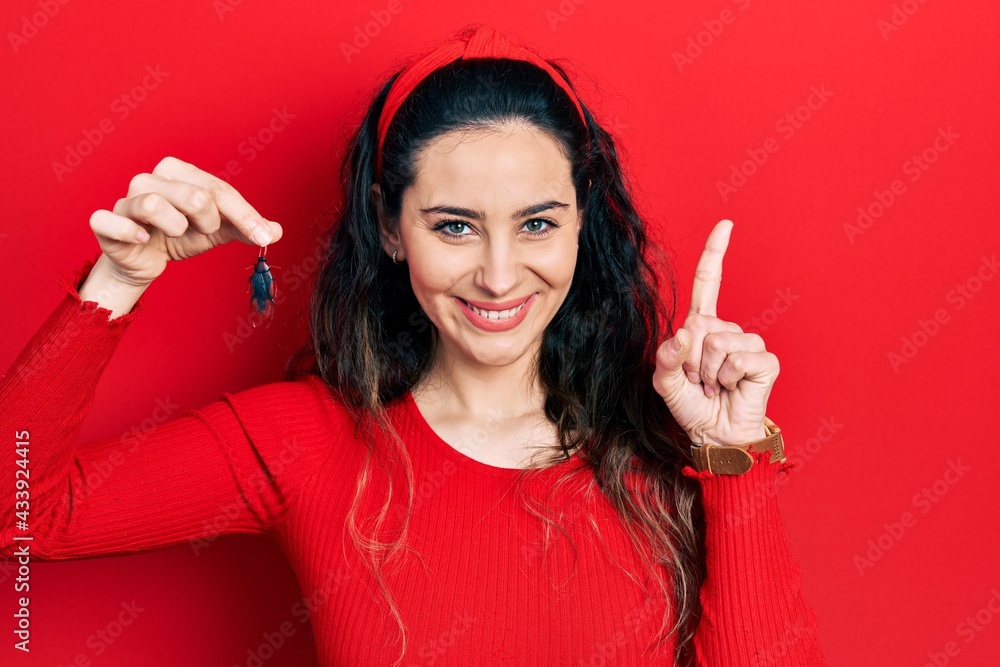 Young hispanic woman holding cockroach surprised with an idea or question pointing finger with happy face, number one Young hispanic woman holding cockroach surprised with an idea or question pointing finger with happy face, number one