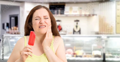 Portrait of a woman with hypersensitivity biting an ice cream in an ice cream parlor .