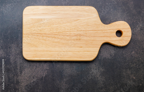 Empty vintage wooden cutting board set up on dark concrete background with copy space.