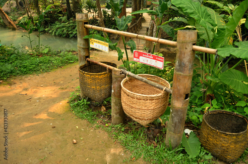 Garbage bamboo wicker basket lao style at bin area for laotian people and foreign travelers dropping waste wait cleaner keeping in Kuang Si Falls or Tat Kuang Si Waterfalls at Luang Prabang, Laos © tuayai