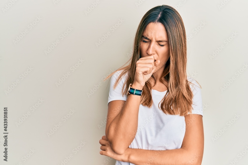 Brunette young woman wearing casual white t shirt feeling unwell and coughing as symptom for cold or bronchitis. health care concept. Brunette young woman wearing casual white t shirt feeling unwell and coughing as symptom for cold or bronchitis. health care concept.