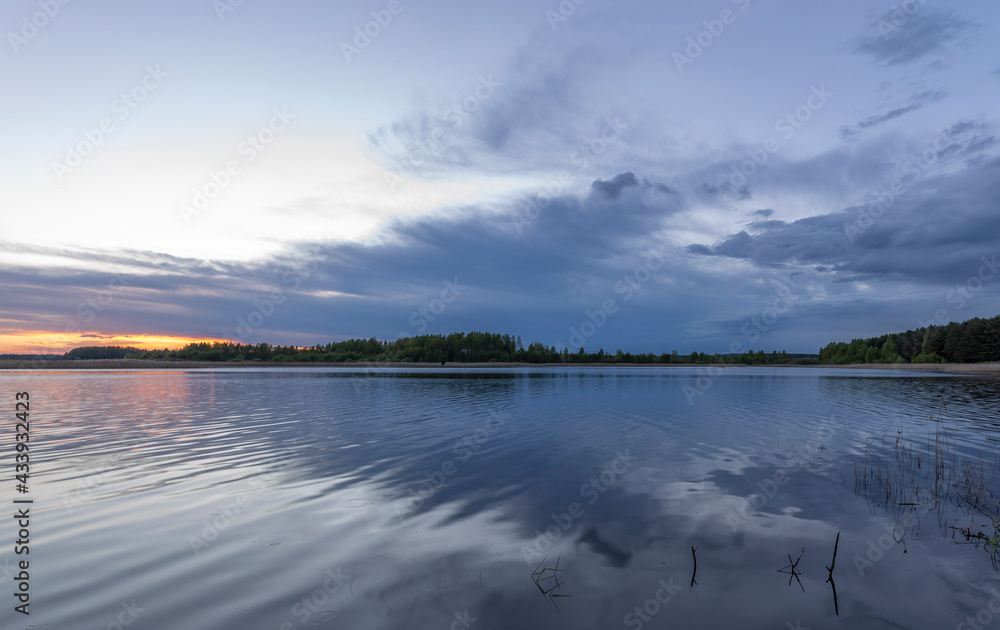 Evening landscape with a river and clouds. Dramatic sunset over the river.