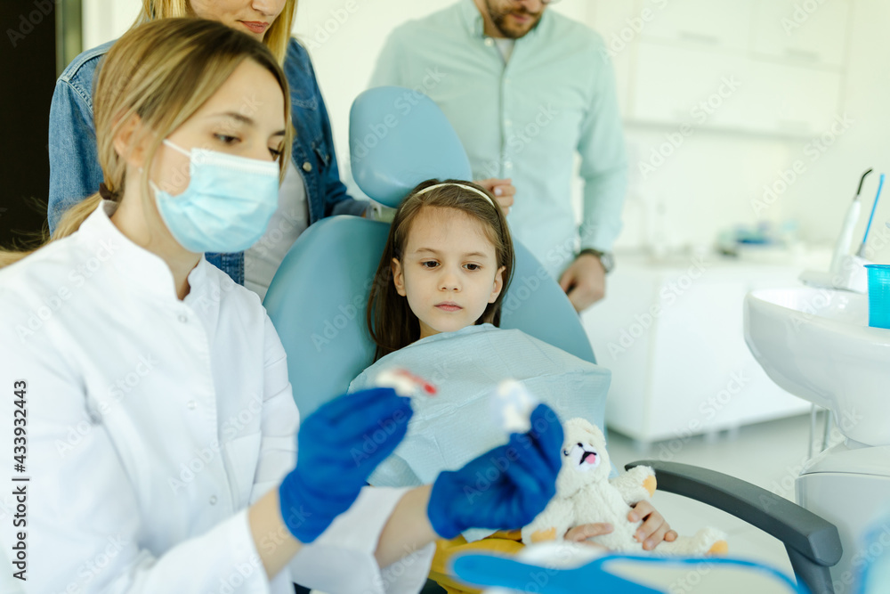 The doctor shows to girl and parents how the prosthesis is used and how it affects the teeth. The doctor shows to girl and parents how the prosthesis is used and how it affects the teeth.