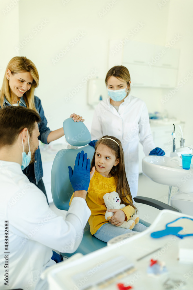 Man doctor is giving hi five to little girl after a successful dental examination. Man doctor is giving hi five to little girl after a successful dental examination.