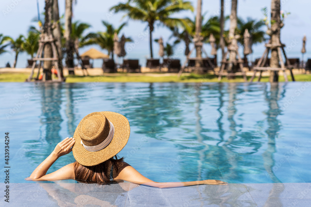 Young woman traveler relaxing and enjoying by a tropical resort pool while traveling for summer vacation, Travel concept