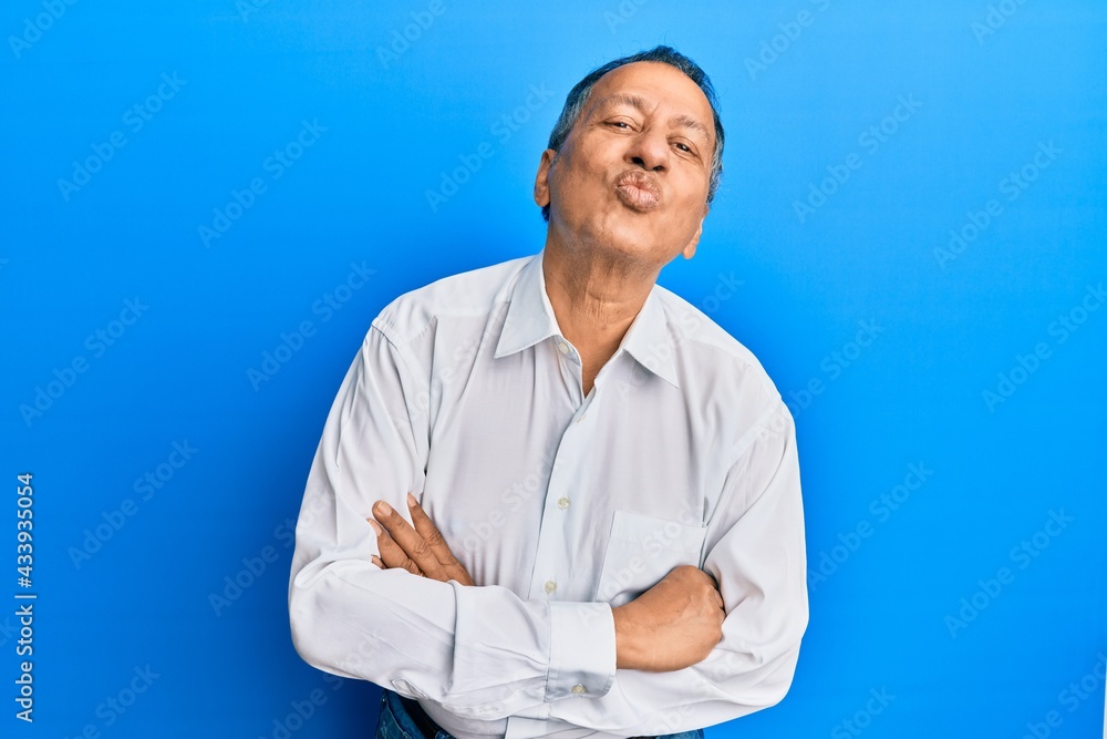 Middle age indian man with arms crossed gesture looking at the camera blowing a kiss being lovely and sexy. love expression. Middle age indian man with arms crossed gesture looking at the camera blowing a kiss being lovely and sexy. love expression.
