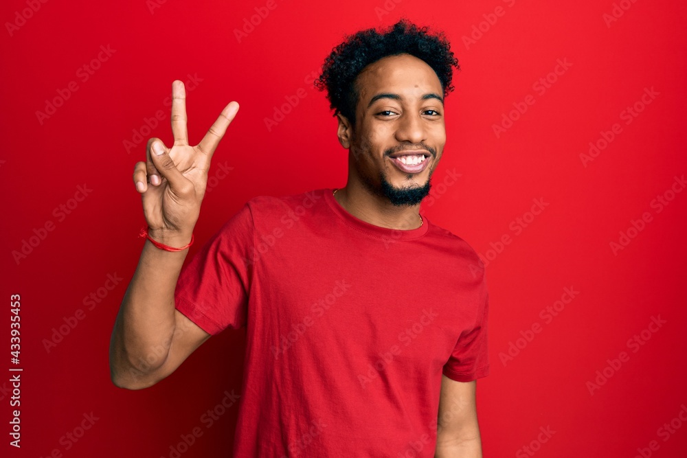Young african american man with beard wearing casual red t shirt showing and pointing up with fingers number two while smiling confident and happy. Young african american man with beard wearing casual red t shirt showing and pointing up with fingers number two while smiling confident and happy.