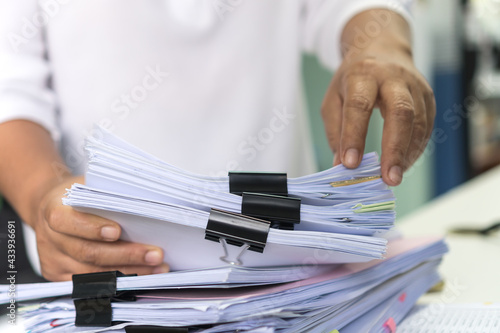 Office workers arranging stacks of lot documents report papers with clips waiting be managed on desk in busy office. Concept of workload in business finacial paperwork information planing photo