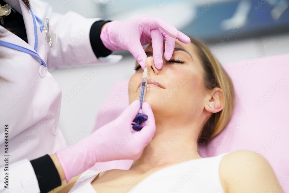 Doctor performing rhinoplasty by injection of hyaluronic acid in the nose of his patient. Doctor performing rhinoplasty by injection of hyaluronic acid in the nose of his patient.