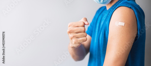 Happy man showing his arm with bandage after receiving vaccine. Vaccination, immunization, inoculation and Coronavirus ( Covid-19 ) pandemic
