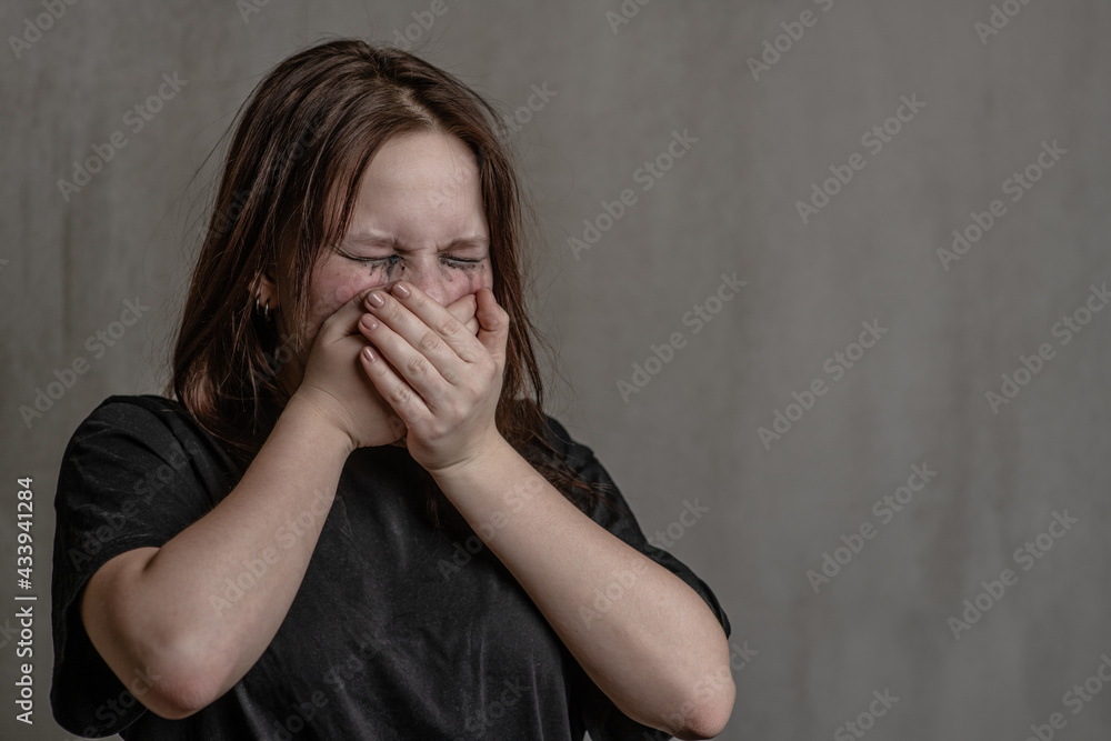 Crying girl covers her mouth with her hands. Empty space for text Crying girl covers her mouth with her hands. Empty space for text