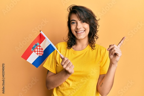 Young hispanic woman holding croatia flag smiling happy pointing with hand and finger to the side