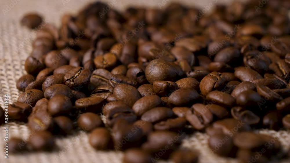 Roasted coffee beans. Smooth motion of arabica coffee seeds. Fragrant coffee beans scrolls slowly around the camera. Slow Motion Close Up of Whole Roasted Robusta Beans