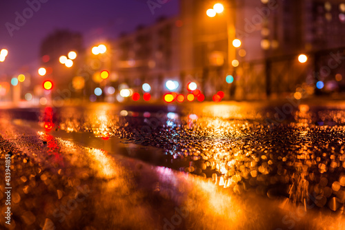 Rainy night in the big city, the empty road with puddles. Close up view from the level of the dividing line