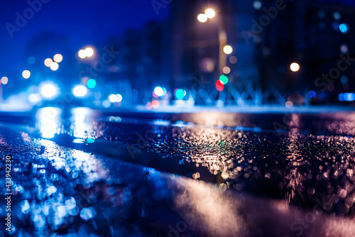 Rainy night in the big city, the approaching car headlights shine through the mist. Close up view from the level of the dividing line