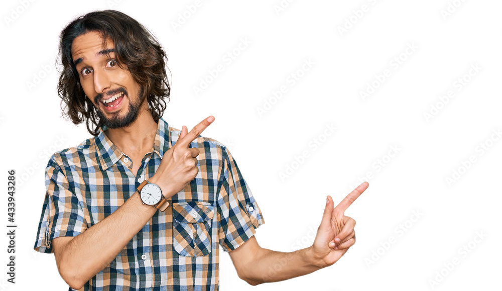 Young hispanic man wearing casual clothes smiling and looking at the camera pointing with two hands and fingers to the side. Young hispanic man wearing casual clothes smiling and looking at the camera pointing with two hands and fingers to the side.
