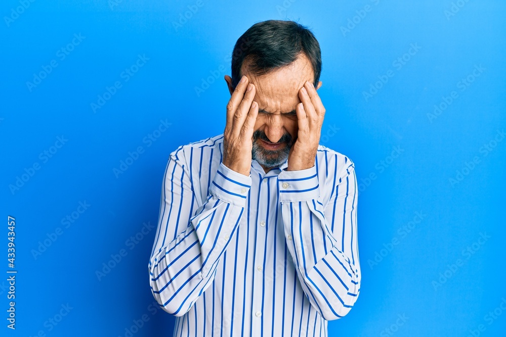 Middle age hispanic man wearing casual clothes with hand on head for pain in head because stress. suffering migraine. Middle age hispanic man wearing casual clothes with hand on head for pain in head because stress. suffering migraine.
