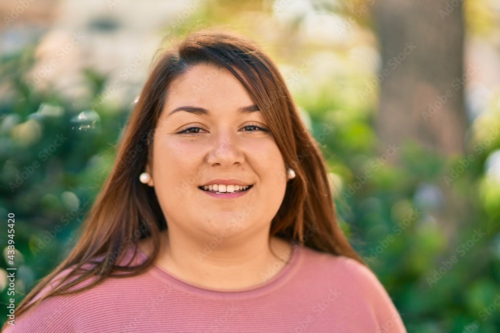 Young hispanic plus size woman smiling happy standing at the park. Young hispanic plus size woman smiling happy standing at the park.