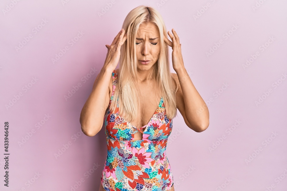 Young blonde woman wearing swimsuit with hand on head for pain in head because stress. suffering migraine. Young blonde woman wearing swimsuit with hand on head for pain in head because stress. suffering migraine.