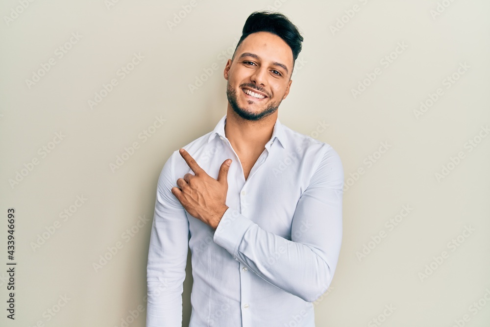 Young arab man wearing casual clothes smiling cheerful pointing with hand and finger up to the side Young arab man wearing casual clothes smiling cheerful pointing with hand and finger up to the side