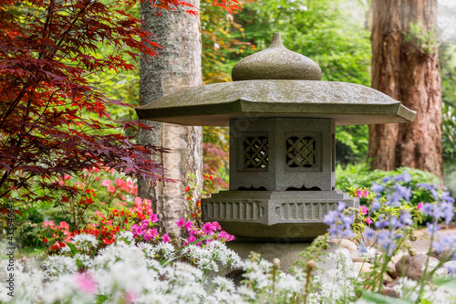 Japanese garden lantern ornament surrounded by flowers and trees photo