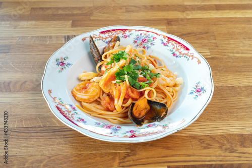 Seafood Pasta with shrimp bolognese sauce on a white plate, tomato sauce with garlic, chili, onion, basil, and, parsley on the wooden background, delicious Italian spaghetti and pasta, food menu. photo