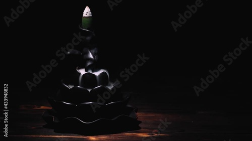 Incense cones holder. Ceramic backflow incense burner in the form of lotus flower. Dark mystic concept.