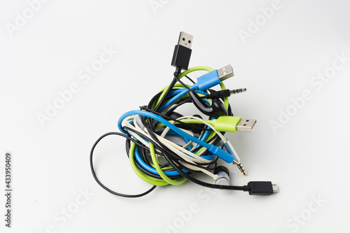 messy wire usb connector and earphone on white background