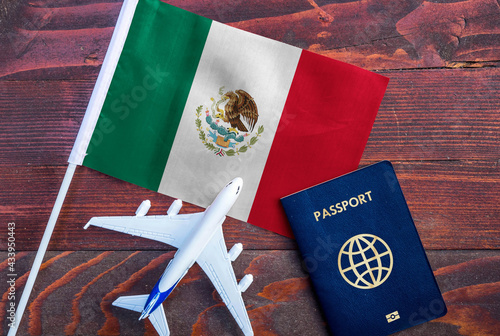 Flag of Mexico with passport and toy airplane on wooden background. Flight travel concept.
