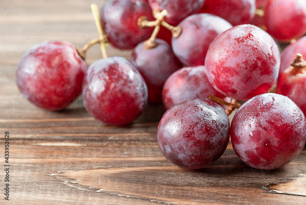 A bunch of pink grapes close-up on a brown wooden background. A bunch of pink grapes close-up on a brown wooden background.
