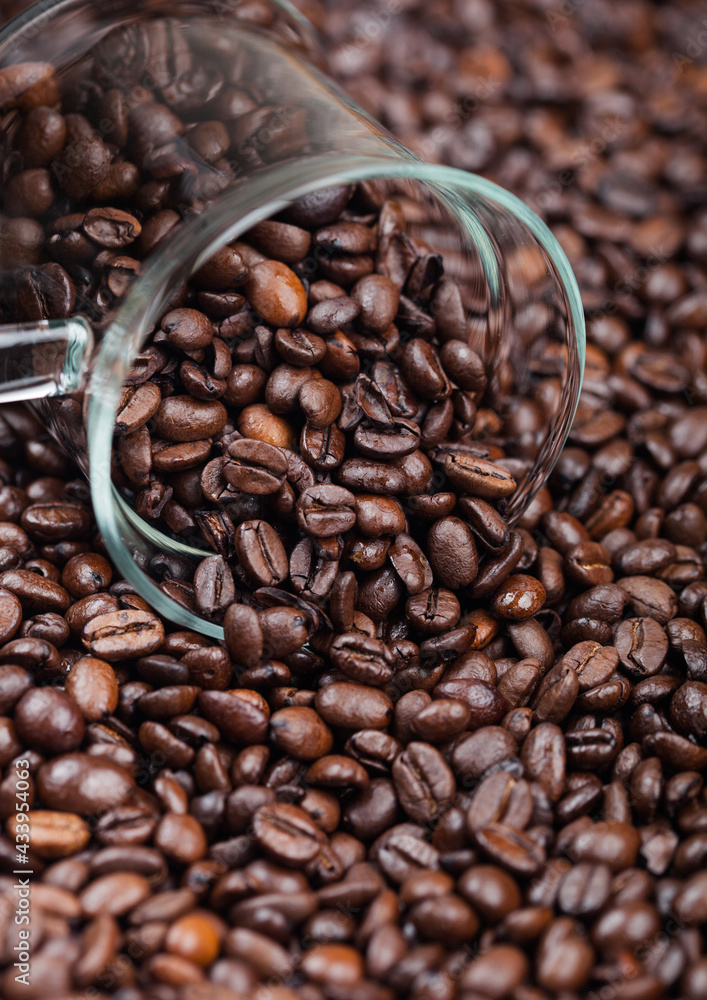 Fototapeta premium Coffee beans in clear glass cup inside coffee beans background.