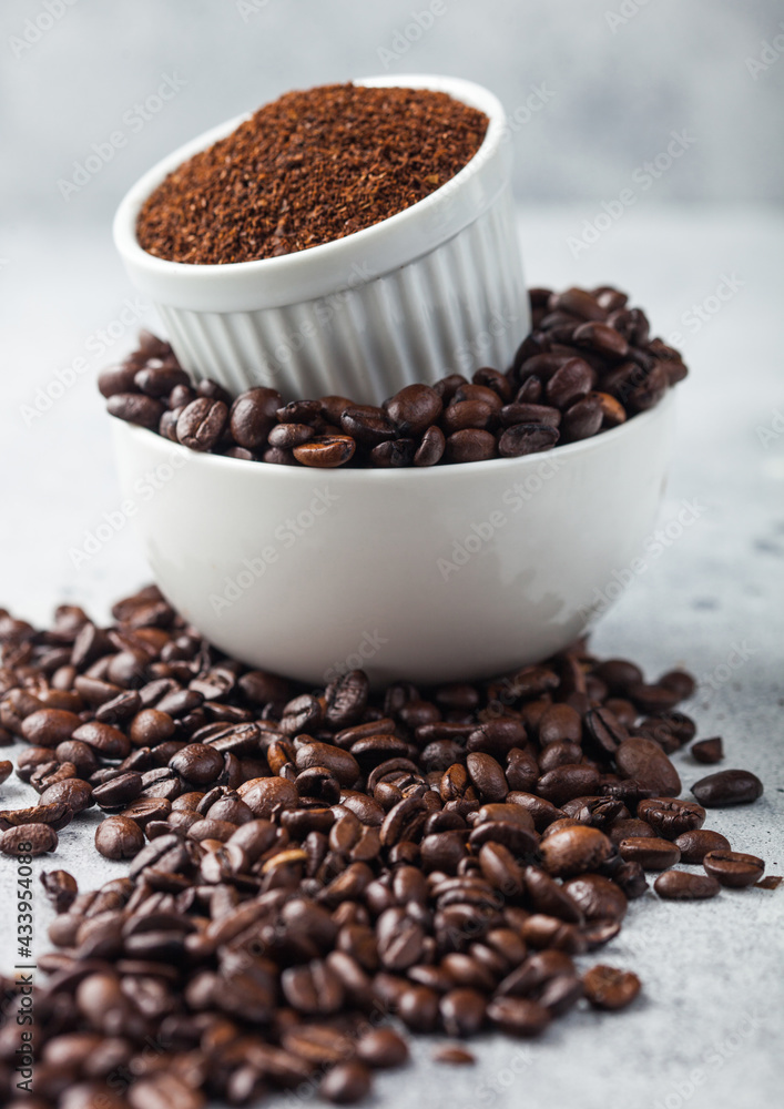 Two bowls on top of each other with fresh raw coffee beans and powder on light background. Two bowls on top of each other with fresh raw coffee beans and powder on light background.
