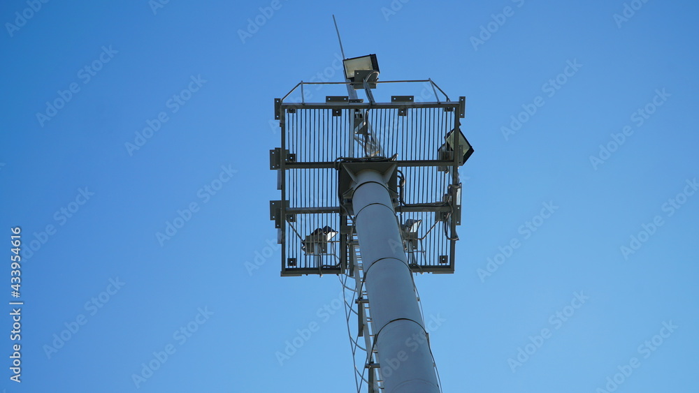 Obraz premium High lighting mast against the blue sky. View from below. Full height.