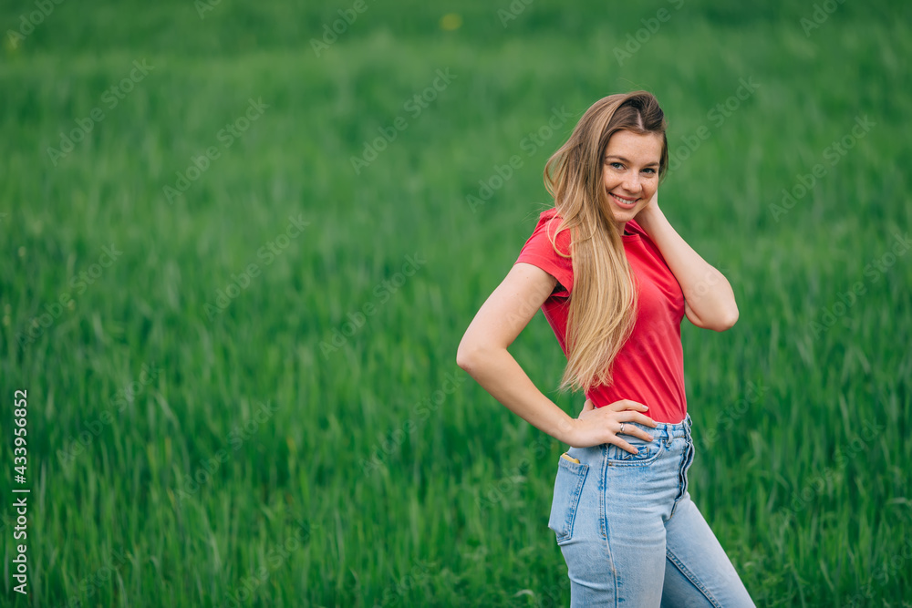 a cheerful girl walks, free, on the grass in the field, dressed in bright daily clothes. a cheerful girl walks, free, on the grass in the field, dressed in bright daily clothes.