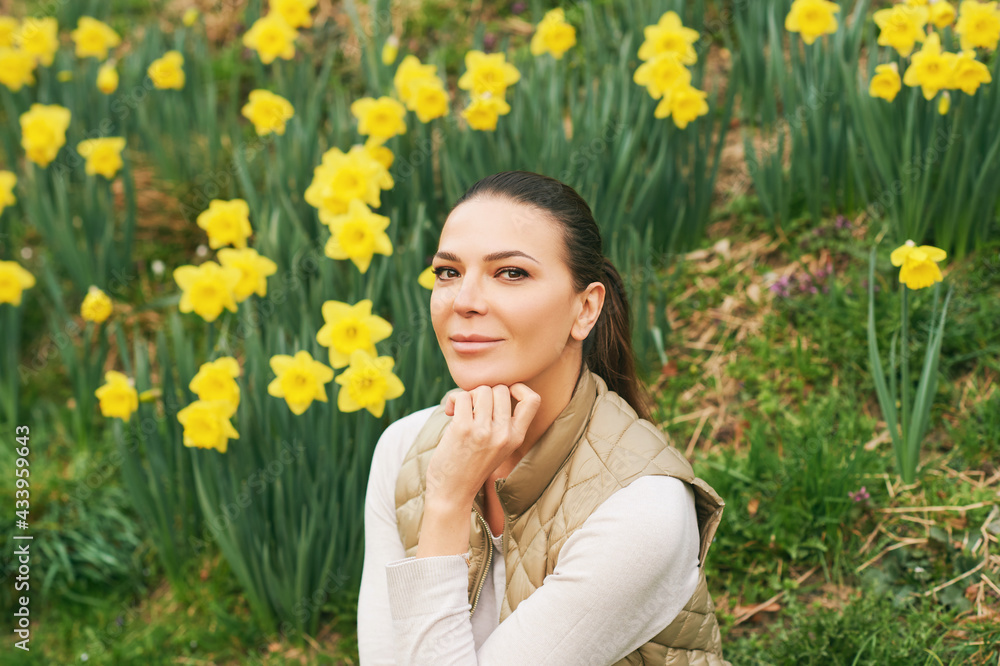 Spring portrait of young beautiful woman sitting in a field of blooming daffodils Spring portrait of young beautiful woman sitting in a field of blooming daffodils