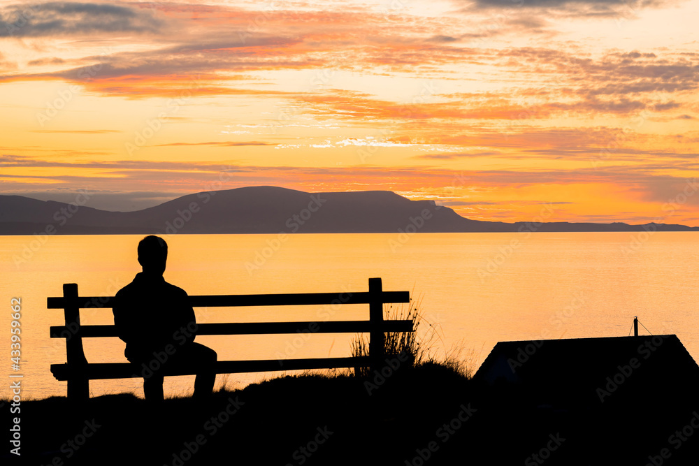 Silhouette of a man sitting on a bench at beautiful sunset. View of the Isle of Skye. Scotland landscape. Silhouette of a man sitting on a bench at beautiful sunset. View of the Isle of Skye. Scotland landscape.