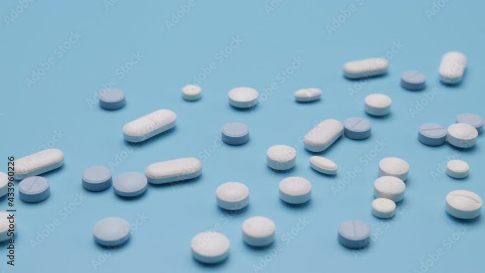 small, white and blue pills on a blue background small, white and blue pills on a blue background