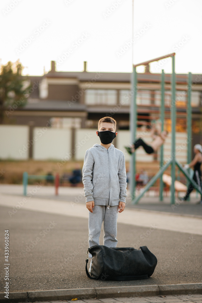A boy stands on a sports field after an outdoor workout during sunset wearing a mask. Healthy lifestyle during the pandemic A boy stands on a sports field after an outdoor workout during sunset wearing a mask. Healthy lifestyle during the pandemic