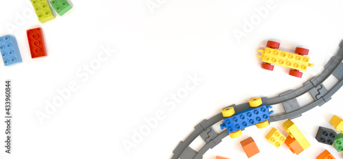 Colorful kids toys flat lay with toy train, railway, plastic and wooden blocks on white background. Children border educational for preschool , playground and kindergarden. Top view. Copyspace.