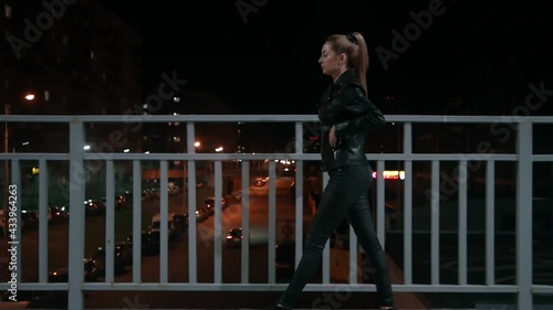 Night time. Blond girl in a leather jacket while walking