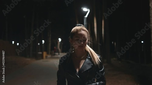 Night time. An attractive girl walks in the park. Lantern