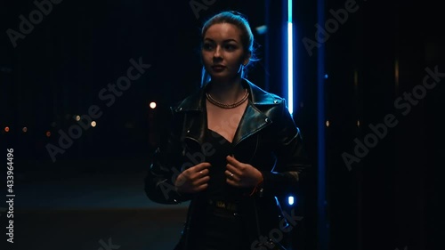 A girl in a leather jacket walks along the night street