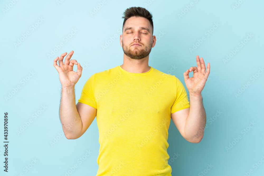 Fototapeta premium Russian handsome man isolated on blue background in zen pose