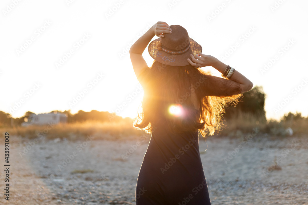 Rear view of a woman wearing a hat at the beach. Soft focus