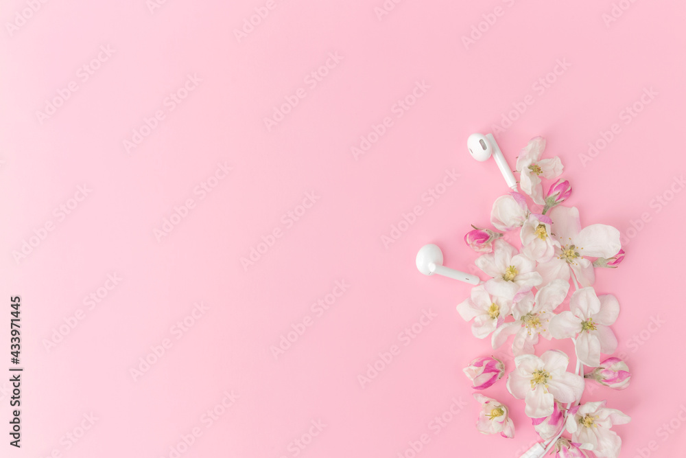 Flat lay on pink background with apple blossom ornament and earphones