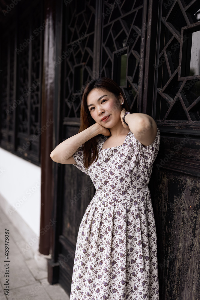 Fototapeta premium Portrait of young asian woman wearing stylish summer dress and walking outdoor in old city. Happy stylish woman with smiley face enjoys life