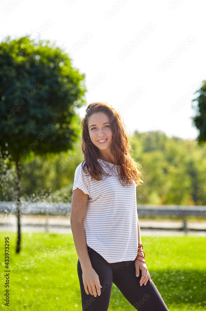 Smiling beautiful girl resting by the nature. Woman in striped t-shirt enjoying summer vacation Smiling beautiful girl resting by the nature. Woman in striped t-shirt enjoying summer vacation
